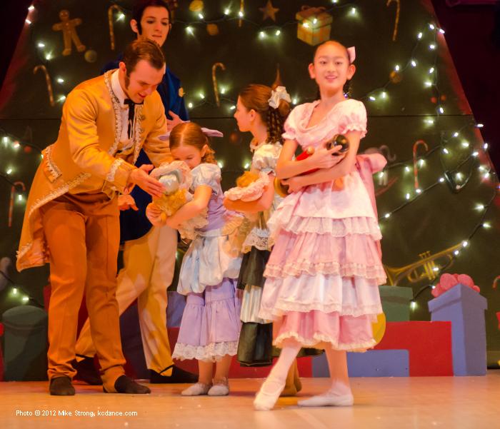 Lisa Kobayashi, (2pm) Clara holding the Nutcracker. Behind are Erik Sobbe (left) and Dalton Heinle (costumed as party guest parents) 