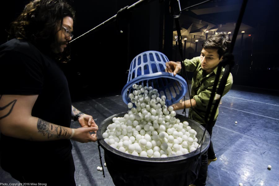 Cleaning up the balls after a performance. Cesar Kastro (right), property manager with Jonah Bokaer dumps a basket of balls into the large kettle used to drop the set of balls for the cascade.